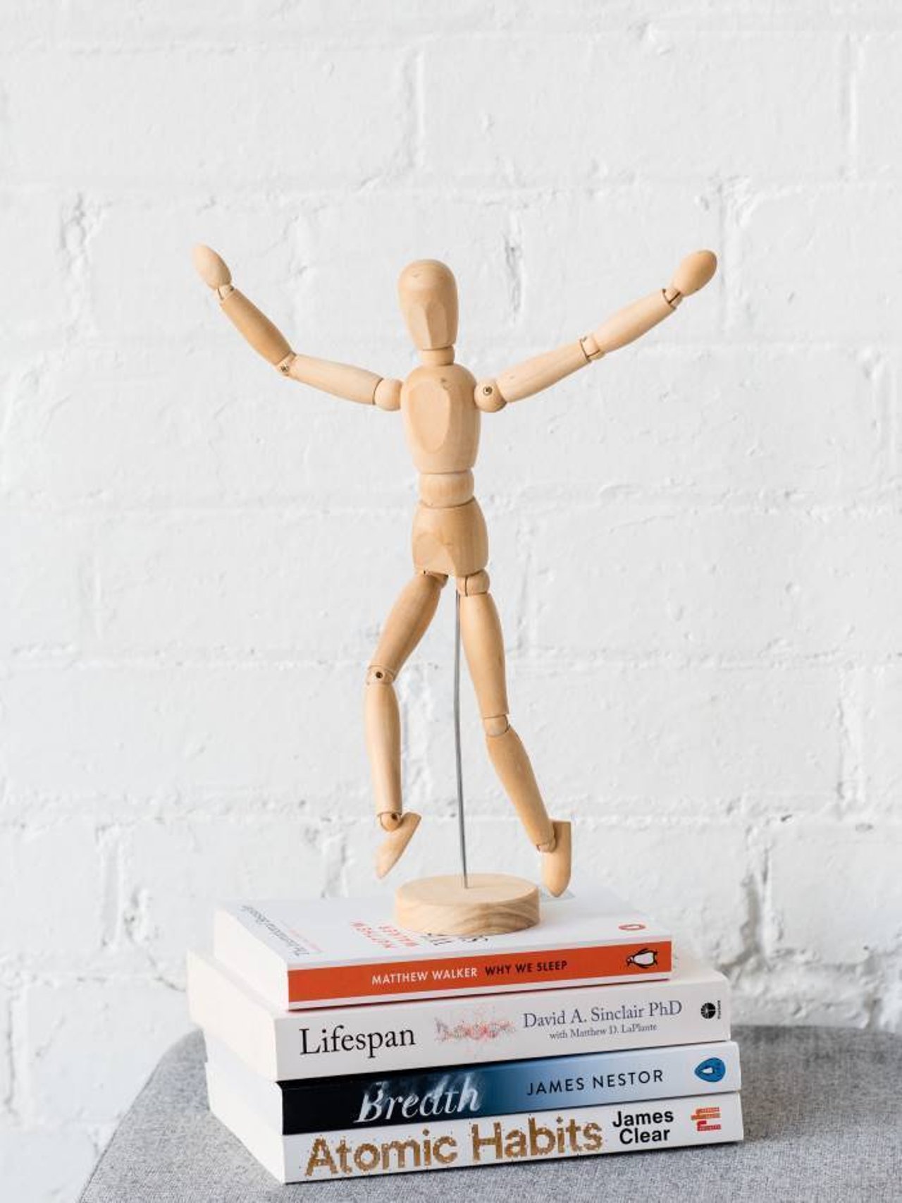 wooden figurine jumping for joy positioned on top of wellness books